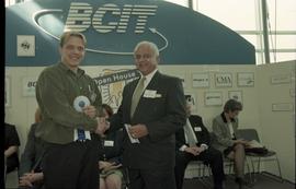 Open House 1998; student holding 1st place ribbon shaking hands with older man in suit [photograp...