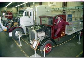 Open House 1998; man sitting in vintage farmer truck with engine exposed and semi truck in backgr...