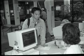 Communications Relations Opening Day 1991;  man listening while registrar worker sits in front of...