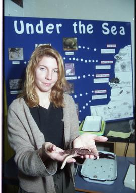 Open House 1998; woman holding starfish in front of under the sea display [photograph 1 of 4]