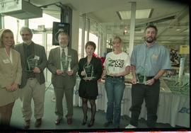 Open House 1998; group of six hold up glass rewards in front of Open House cake