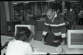 Communications Relations Opening Day 1991;  man leaning over registrar desk while registrar worke...