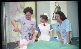 Open House 1998; two nursing students with old fashion nursing dummy pose with wounded dummy [pho...