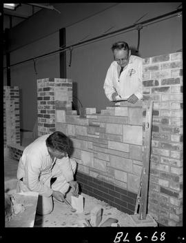 B.C. Vocational School image of a Bricklaying student building with bricks with an instructor che...