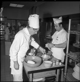 BC Vocational School Cook Training Course ; student preparing food while the instructor tests the...