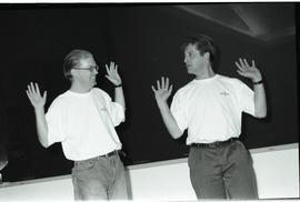Communications Relations Opening Day 1991; two men in orientation shirts holding up hands