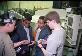 Open House 1998; Welsey Connor and student in welder's mask holding metal objects while standing ...