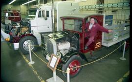 Open House 1998; man sitting in vintage farmer truck with engine exposed and semi truck in backgr...