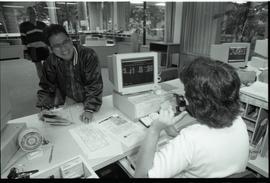 Communications Relations Opening Day 1991;  man smiling to registrar worker sitting in front of c...