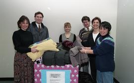 Staff members with a box labeled "Warm clothes and blankets for the needy" [3 of 5 phot...