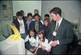 Open House 1998; man in suit explains what is on computer to crowd of young students