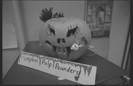 Carved pumpkin with a "pumpkin pulp pounders" signs