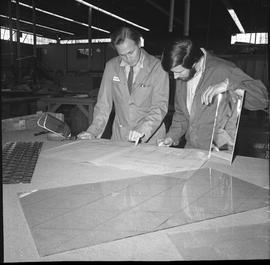 BCVS Glazier program ; two men looking at blueprints ; a large piece of glass on the table