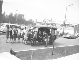 Students standing around a car from the 1920s(?) on campus