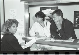 Communications Relations Opening Day 1991; two men leaning against counter while woman walks up w...