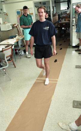 Man walking on paper creating ink footprints [2 of 9 photographs]