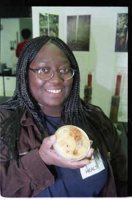 Open House 1998; student holding up bacteria growth in petri dish [photograph 1 of 2]