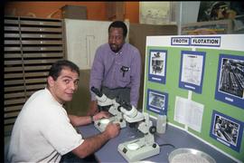 Open House 1998; two men with microscopes in front of froth flotation display [photograph 1 of 2]