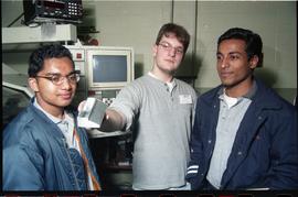 Open House 1998; Wesley Connor holding metal object between two students [photograph 1 of 2]