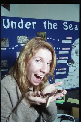 Open House 1998; woman holding starfish in front of under the sea display [photograph 4 of 4]