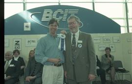 Open House 1998; student grinning with bearded man in suit holding first prize ribbon [photograph...