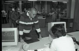 Communications Relations Opening Day 1991;  man leaning over registrar desk while registrar worke...