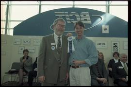 Open House 1998; student grinning with bearded man in suit holding first prize ribbon [photograph...