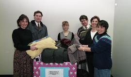 Staff members with a box labeled "Warm clothes and blankets for the needy" [5 of 5 phot...