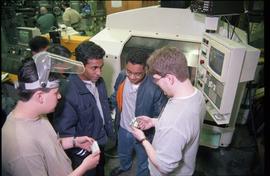 Open House 1998; Welsey Connor and student in welder's mask holding metal objects while standing ...
