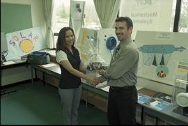 Open House 1998; man giving woman prize in front of solar power displays [photograph 3 of 3]