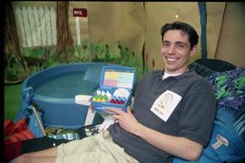 Open House 1998; man wearing environmental health shirt displays box filled with bottles [photogr...