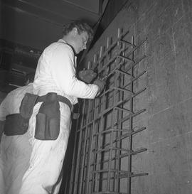 Structural steel, 1971; man cutting wires on a steel grid