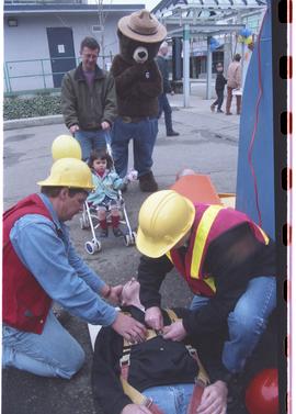 Open House 1998; two men demonstrating placing another man on first aid board while Smokey the Be...