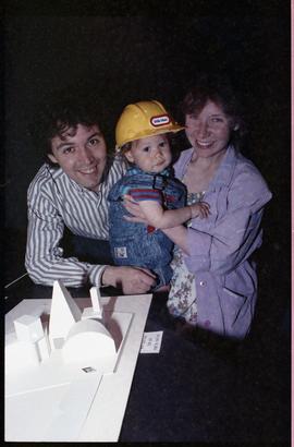 Open House 1992; couple posing with toddler in front of  guest house model [photograph 2 of 3]