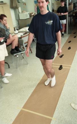 Man walking on paper creating ink footprints [3 of 9 photographs]