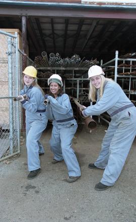 BCIT women in trades; plumbing, students in uniforms and hard hats carrying piping material [3 of...