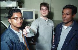 Open House 1998; Wesley Connor holding metal object between two students [photograph 2 of 2]