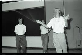 Communications Relations Opening Day 1991; three men in orientation shirts improvising/speaking