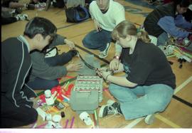 Open House 1998; two high school students taking out strip of duct tape over egg cartons