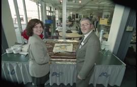 Open House 1998; man and woman hold knives over Open House chocolate cake [photograph 2 of 3]