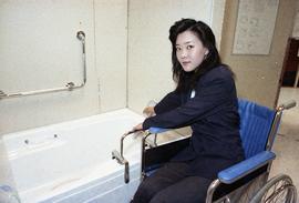 Open House 1992; woman in wheelchair turning bathtub faucet with safety bars [photograph 3 of 3]