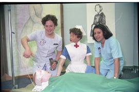 Open House 1998; two nursing students with old fashion nursing dummy pose with wounded dummy [pho...