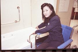 Open House 1992; woman in wheelchair turning bathtub faucet with safety bars [photograph 2 of 3]