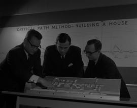 Business Management; three men looking at a miniature model of a store layout [1 of 2]