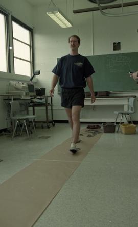 Man walking on paper creating ink footprints [6 of 9 photographs]