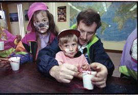 Open house 1992; children stare away from camera as father focuses on arts and crafts