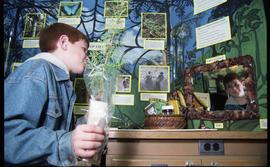 Open House 1998; child holding plant staring at who can help mirror on display