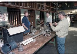 Open House 1986; man holds acid waste pipe in front of students