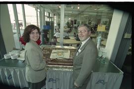 Open House 1998; man and woman hold knives over Open House chocolate cake [photograph 1 of 3]