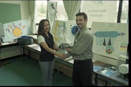 Open House 1998; man giving woman prize in front of solar power displays [photograph 1 of 3]